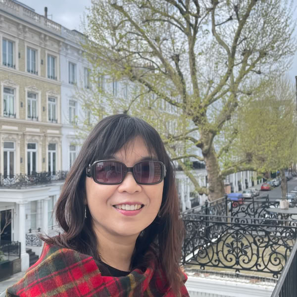 Asian woman working as a call center agent, smiling at desk with documents and headset.